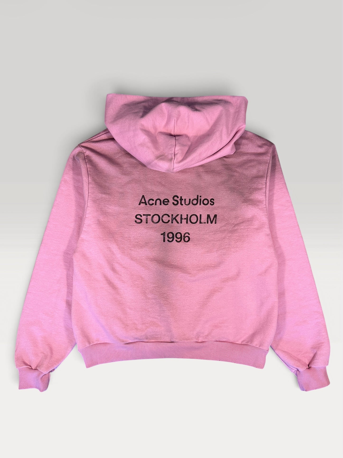 Acne Studios STOCKHOLM 1996 logo print across the back of the pink hoodie