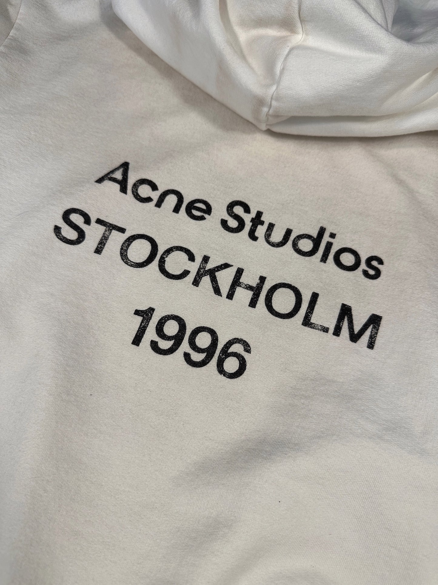 Close-up of the cracked Acne Studios STOCKHOLM 1996 print on the off-white hoodie