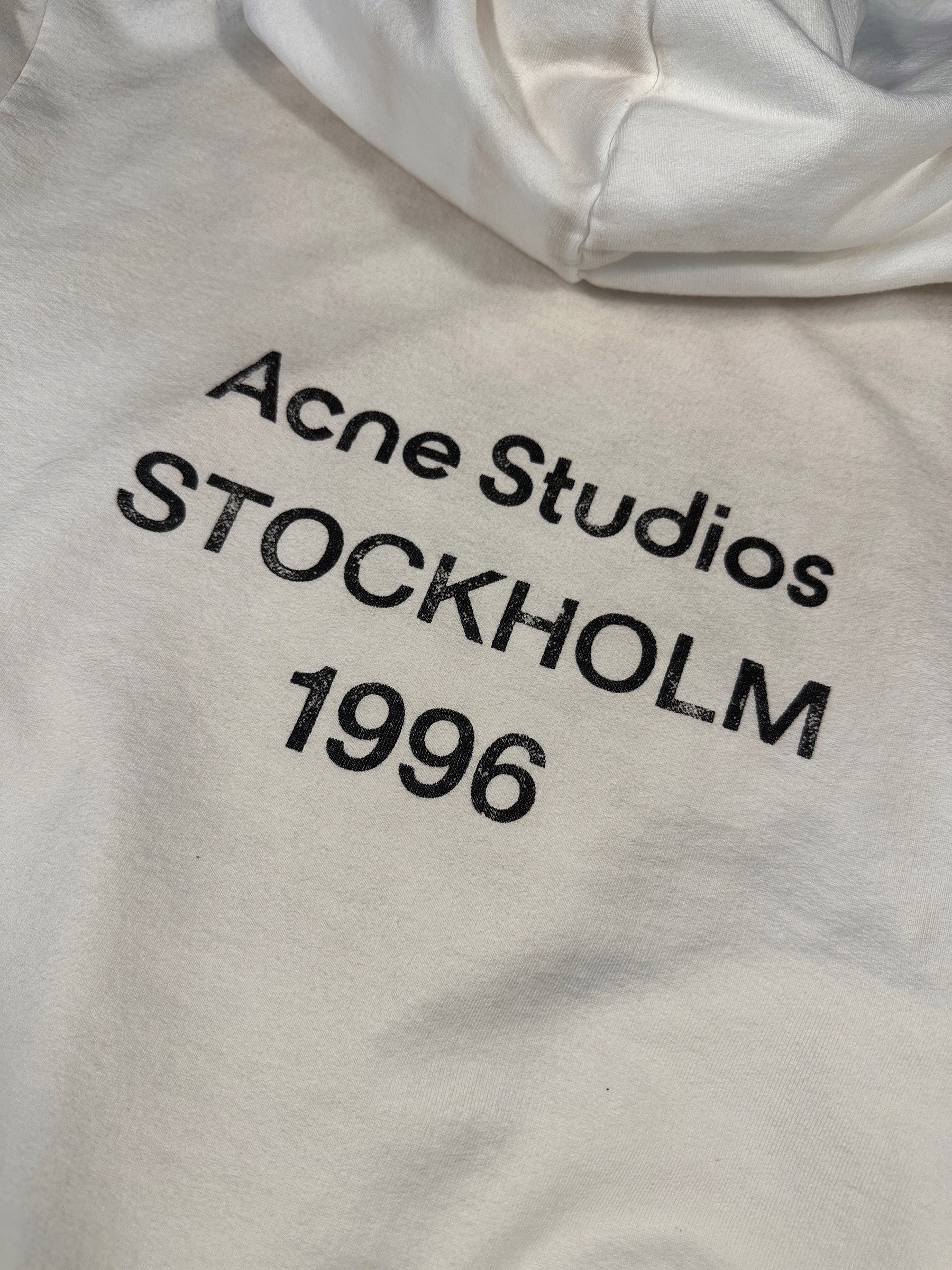 Close-up of the cracked Acne Studios STOCKHOLM 1996 print on the off-white hoodie